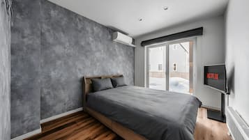 Un dormitorio moderno con cama, televisor y vistas al exterior.
