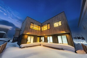 A modern two-story house with large windows and a snow-covered driveway. - TDR Toti Design Room (Furano)