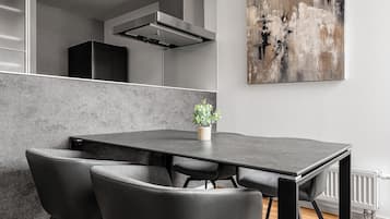 Un moderno comedor con una mesa y sillas negras, una planta en maceta y un cuadro abstracto grande en la pared.