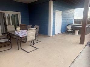 A covered patio with a table and chairs, a door, and a hot tub. - Lush stay at Jamaica Beach RV resort. Enjoy all amenities of the resort as well! (Galveston)