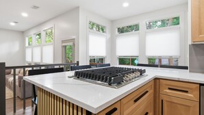 Una cocina moderna con una isla central, armarios de madera y ventanas amplias.