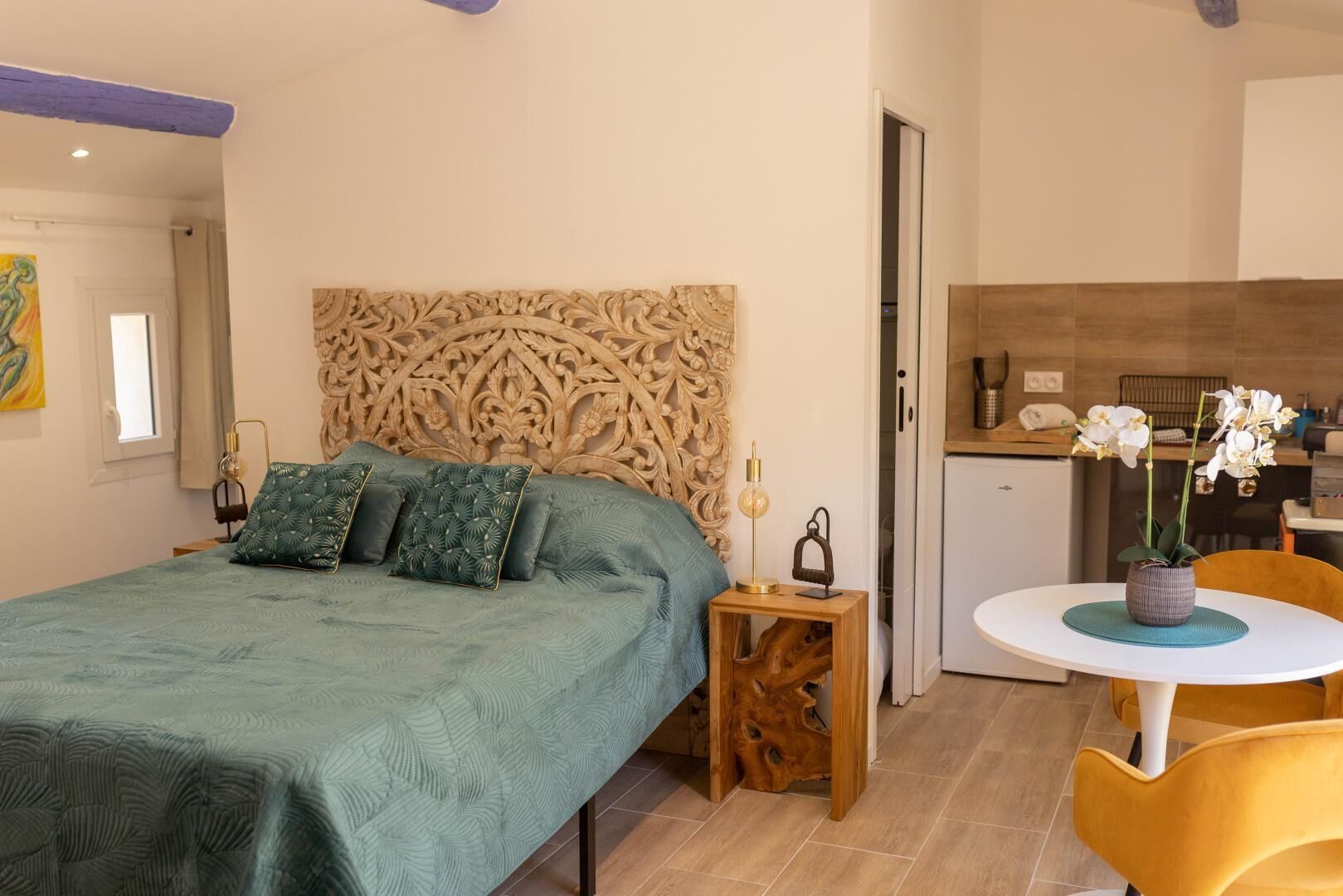 Una camera da letto con un letto grande, una testiera in legno, un comodino con una lampada e un tavolino con un vaso di fiori.