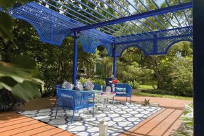 Una pérgola azul con asientos y un suelo estampado.
