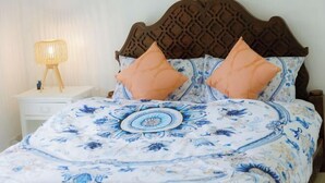 Un lit bien fait, avec une couvre-lit à motifs floraux, deux oreillers assortis et une tête de lit en bois.