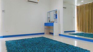 Une pièce avec un tapis bleu, un miroir et un meuble dont le cadre est bleu.