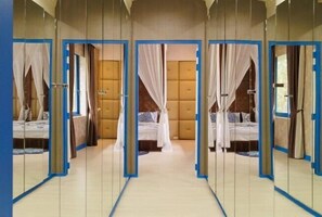 Una habitación con paredes espejadas, una cama con dosel y un cabecero capitonado.