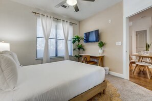 Ein Schlafzimmer mit einem Bett, einem Schreibtisch, einem Fernseher und einer Essecke.