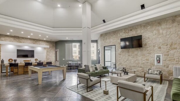 A spacious living area with a pool table, sofas, and a stone wall. - Luxury 1B w Pool near Legacy West (Frisco)