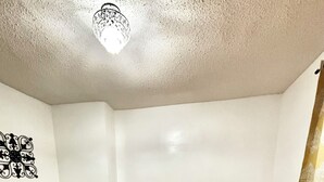 Et soveværelse med to senge, en stol, en lampe og en dekorativ vægdekoration.