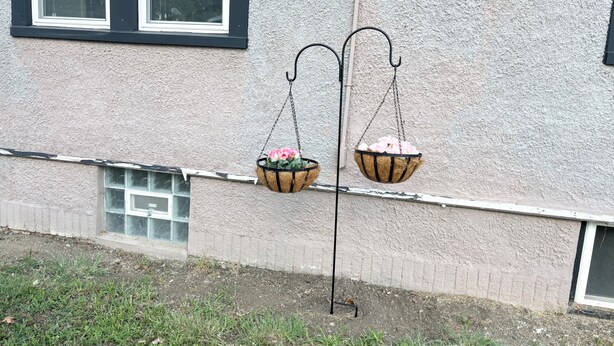 En bygnings facade med to blomsterkurve hængende på et metalstativ.