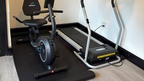 Et hjemmegymnasium med motionscykel, crosstrainer og løbebånd.