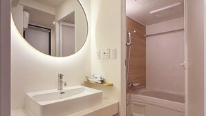A modern bathroom with a white sink, a round mirror, and a walk-in shower. - b hotel Tekkyodo (Hiroshima)