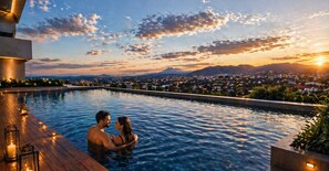 A couple in a swimming pool with a cityscape and mountains in the background. - Vista Tower, Apartamento 3 hab. piscina, gym, rooftop (San Salvador)