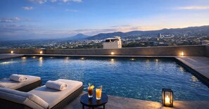 A rooftop pool with lounge chairs, a table with drinks, and a cityscape view in the background. - Vista Tower, Apartamento 3 hab. piscina, gym, rooftop (San Salvador)