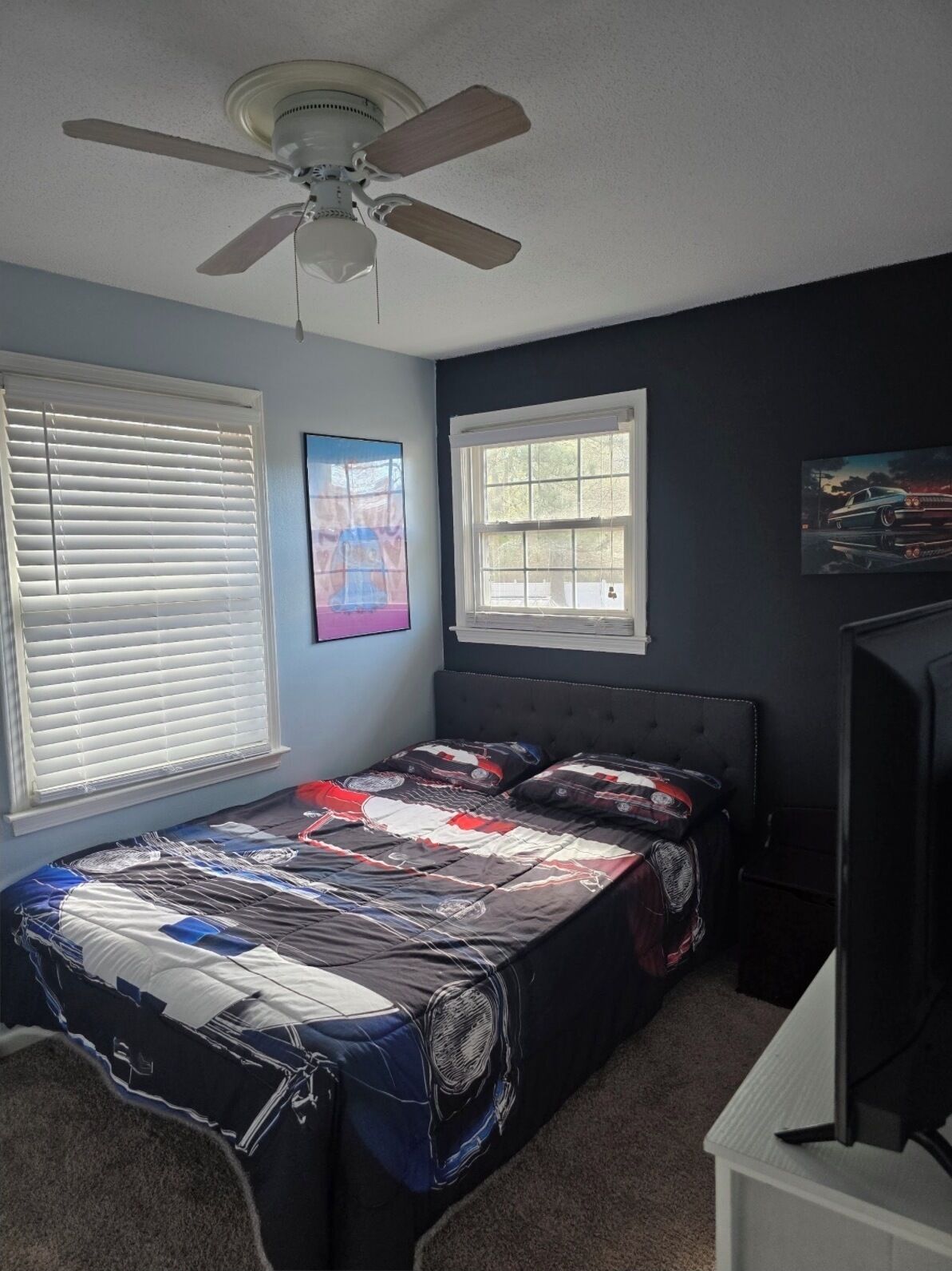 Quarto com uma cama, ventoinha no teto, janela e um quadro na parede.