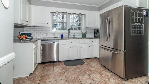 A kitchen with white cabinets, a stainless steel refrigerator, a dishwasher, and a window above the sink. - Masters Week Golf Retreat-4BR Home on Golf Course (Augusta)
