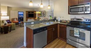 A modern kitchen with a dishwasher, oven, and microwave. There is a dining area with a table and chairs. - Relaxing 1-bedroom resort with AC in marvelous Las Vegas (Las Vegas)