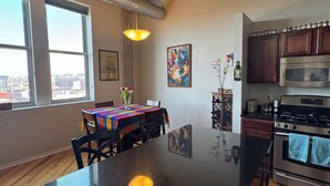 Cocina moderna con una isla grande, electrodomésticos de acero inoxidable y ventanas amplias con vistas a la ciudad.