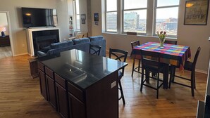 Cocina moderna con una isla grande, piso de madera e iluminación colgante.