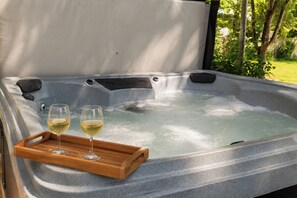 Un bain à remous avec deux verres de vin blanc posés sur un plateau en bois.