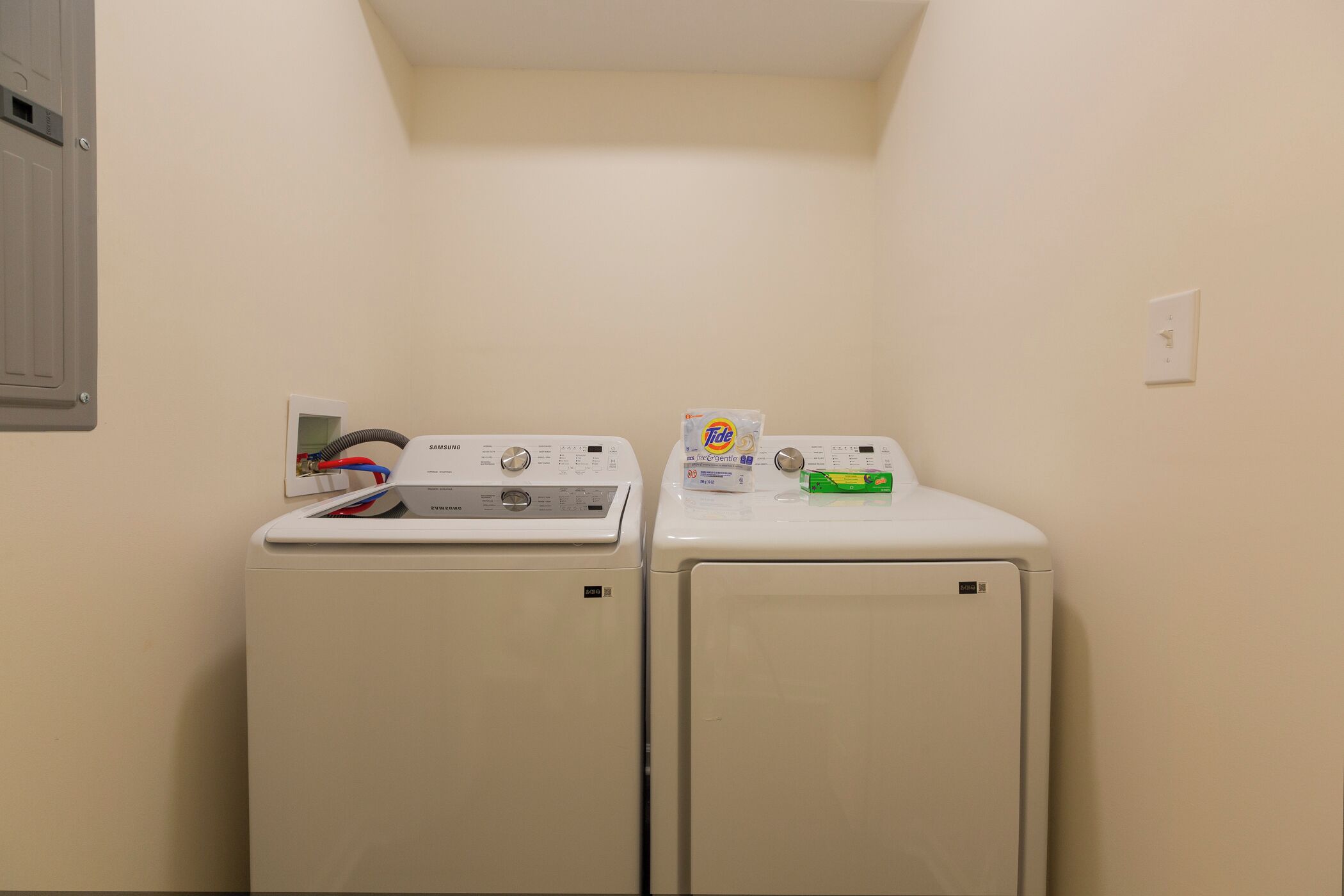 A laundry room with two front-loading washing machines and a dryer.
