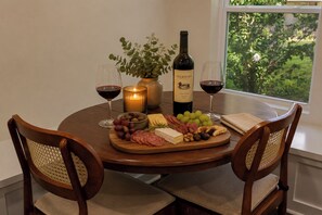 A round dining table with a bottle of Duckhorn wine, glasses, a candle, and a variety of cheeses and cured meats. - Hot Tub- Sleeps 10- Bourbon Trail- Historic Home (Coxs Creek)