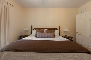 A bedroom with a bed, two bedside tables, a door, and a curtain. - Hot Tub- Sleeps 10- Bourbon Trail- Historic Home (Coxs Creek)