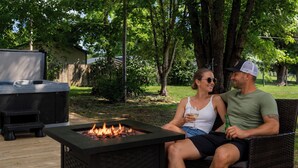 A couple sitting on a wicker bench with a fire pit in the foreground. - Hot Tub- Sleeps 10- Bourbon Trail- Historic Home (Coxs Creek)