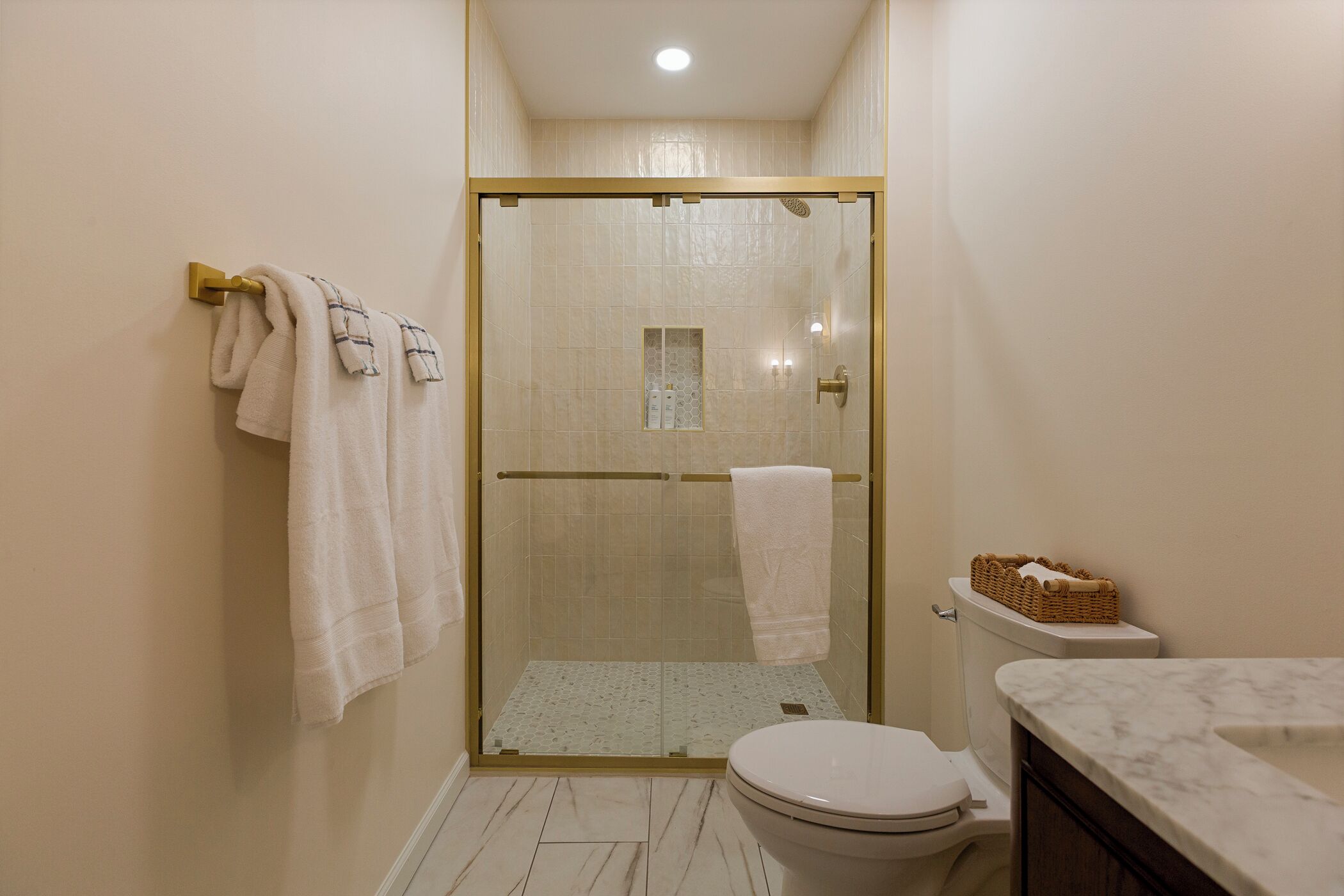 A bathroom with a glass-enclosed shower, a toilet, and a marble countertop.
