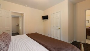 A bedroom with a bed, a television mounted on the wall, and a door leading to another room. - Hot Tub- Sleeps 10- Bourbon Trail- Historic Home (Coxs Creek)