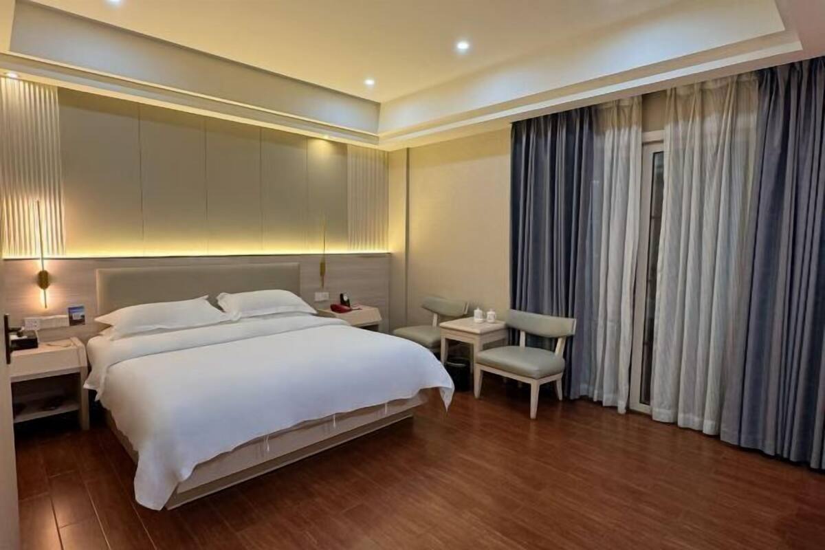 A modern hotel room with a large bed, bedside tables, a desk, and a chair.