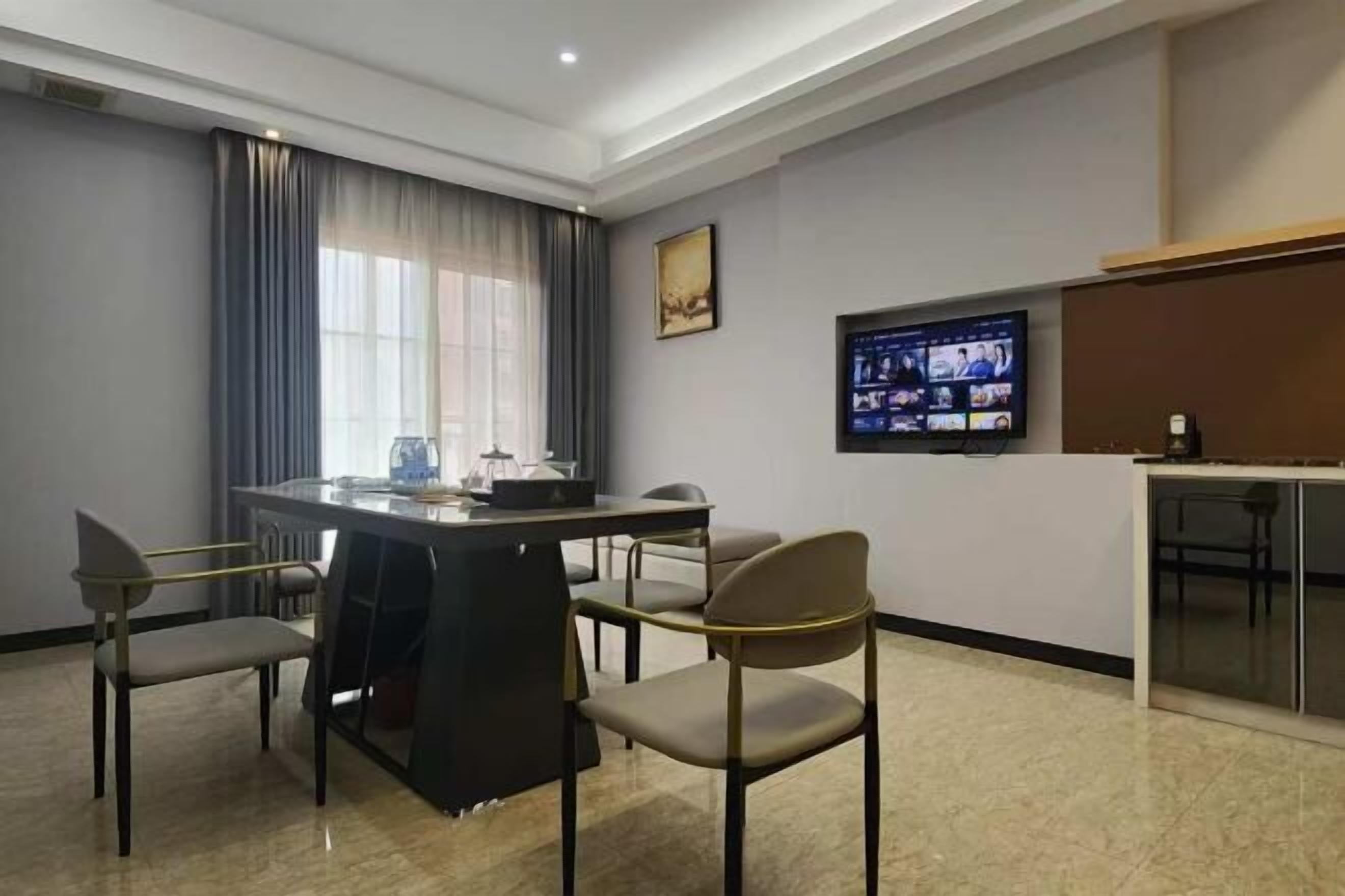 A modern hotel room with a dining area, a television, and a minibar.