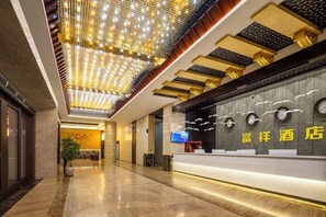 A hotel reception area with a modern design, featuring a reception desk, a digital screen, and a ceiling with decorative lighting. - Puning · Fu Xiang Audio-Visual Landscape Hotel (Puning)