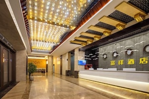 Uma área de recepção de hotel com design moderno, apresentando um balcão de atendimento, uma tela digital e um teto com iluminação decorativa.