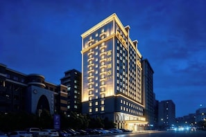 A multi-story hotel with a prominent entrance, large windows, and a well-lit facade. - Puning · Fu Xiang Audio-Visual Landscape Hotel (Puning)