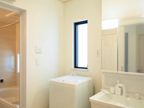 A bathroom with a white sink, a window, and a mirror.