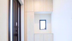 Pasillo con un armario de madera, una ventana pequeña y una puerta.