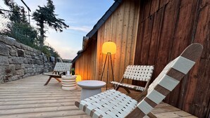 A wooden deck with a stone wall, a wooden building, and two wicker lounge chairs. - NEU!   dasErbhaus by Interhome (Grossschönau)