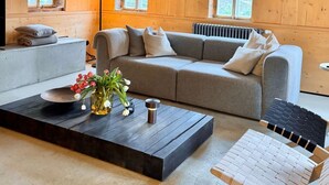 A cozy living room with a grey sofa, a coffee table with a vase of flowers, and a wooden ceiling. - NEU!   dasErbhaus by Interhome (Grossschönau)