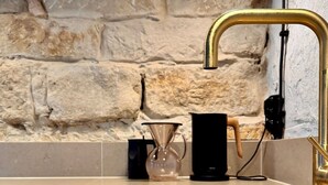 A kitchen with a stone wall, a gold faucet, and a coffee maker on the counter. - NEU!   dasErbhaus by Interhome (Grossschönau)