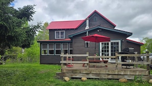 A two-story house with a red roof, a deck with a red umbrella, and a grill area. - S'More the Merrier! 3BR/3BA Indian Lake escape. Year round family memories & fun (Indian Lake)