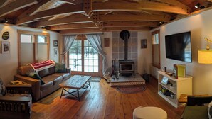 A cozy living room with a fireplace, wooden floors, a sofa, and a television. - S'More the Merrier! 3BR/3BA Indian Lake escape. Year round family memories & fun (Indian Lake)