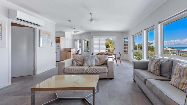 Ein modernes Wohnzimmer mit einem Glastisch, zwei Sofas und Blick aufs Meer.