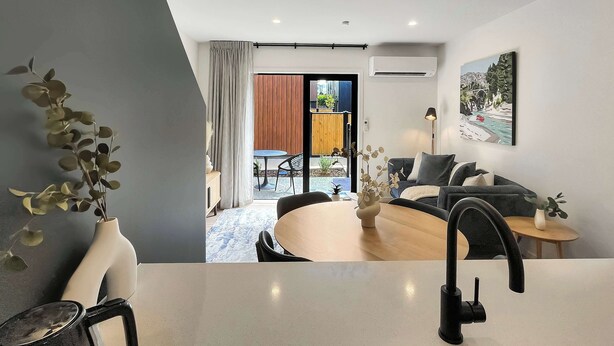 A modern living room with a sofa, a coffee table, and a dining area with a table and chairs.