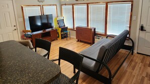 Una sala de estar con televisión, un sofá, una mesa de comedor y un ventilador de techo.
