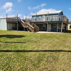 Un bâtiment à deux étages doté d’une terrasse en bois et d’un escalier menant à l’étage supérieur.