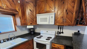 Una cocina con armarios de madera, una estufa blanca, un microondas y un lavabo.
