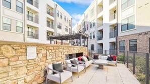 Un patio con mobiliario exterior, paredes de piedra y una chimenea.