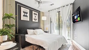 Una habitación de hotel moderna con una cama, un televisor, un escritorio con una silla y una planta en maceta.