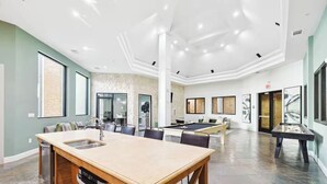 Amplia sala de estar con mesa de billar, cocina con isla de madera y comedor con mesa grande.